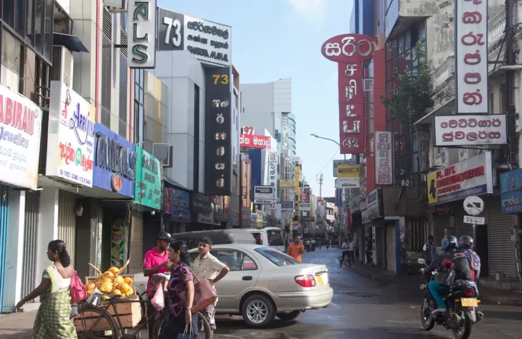 A busy street with shops on either side, and vehicles parked along it