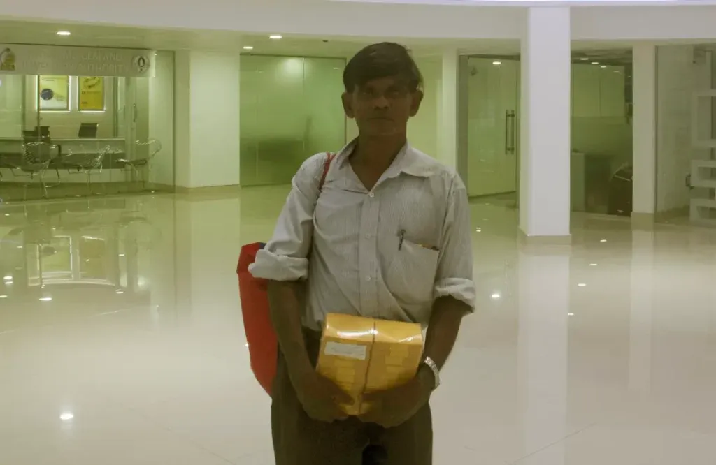 A man with a yellow package in his hands and a red bag hanging by his side