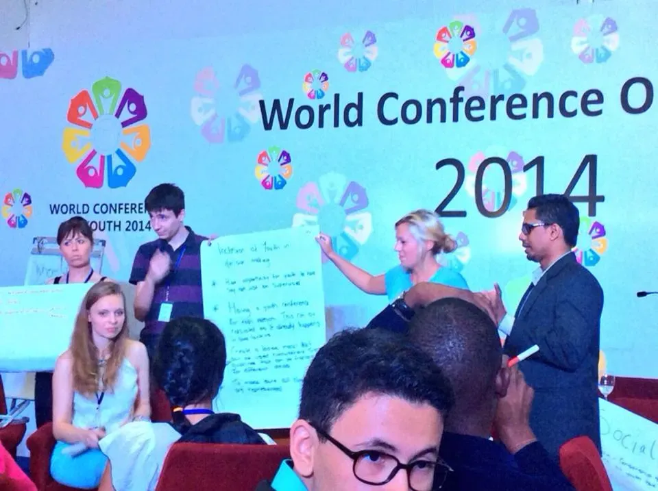 Delegates holding a large sheet of paper and presenting to a room