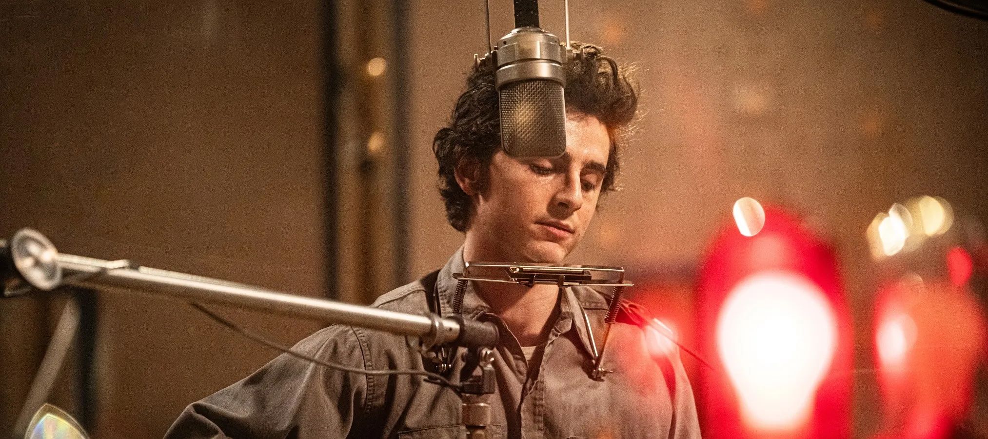 Timothée Chalamet as Bob Dylan, behind two microphones getting ready for a performance in a still from the film
