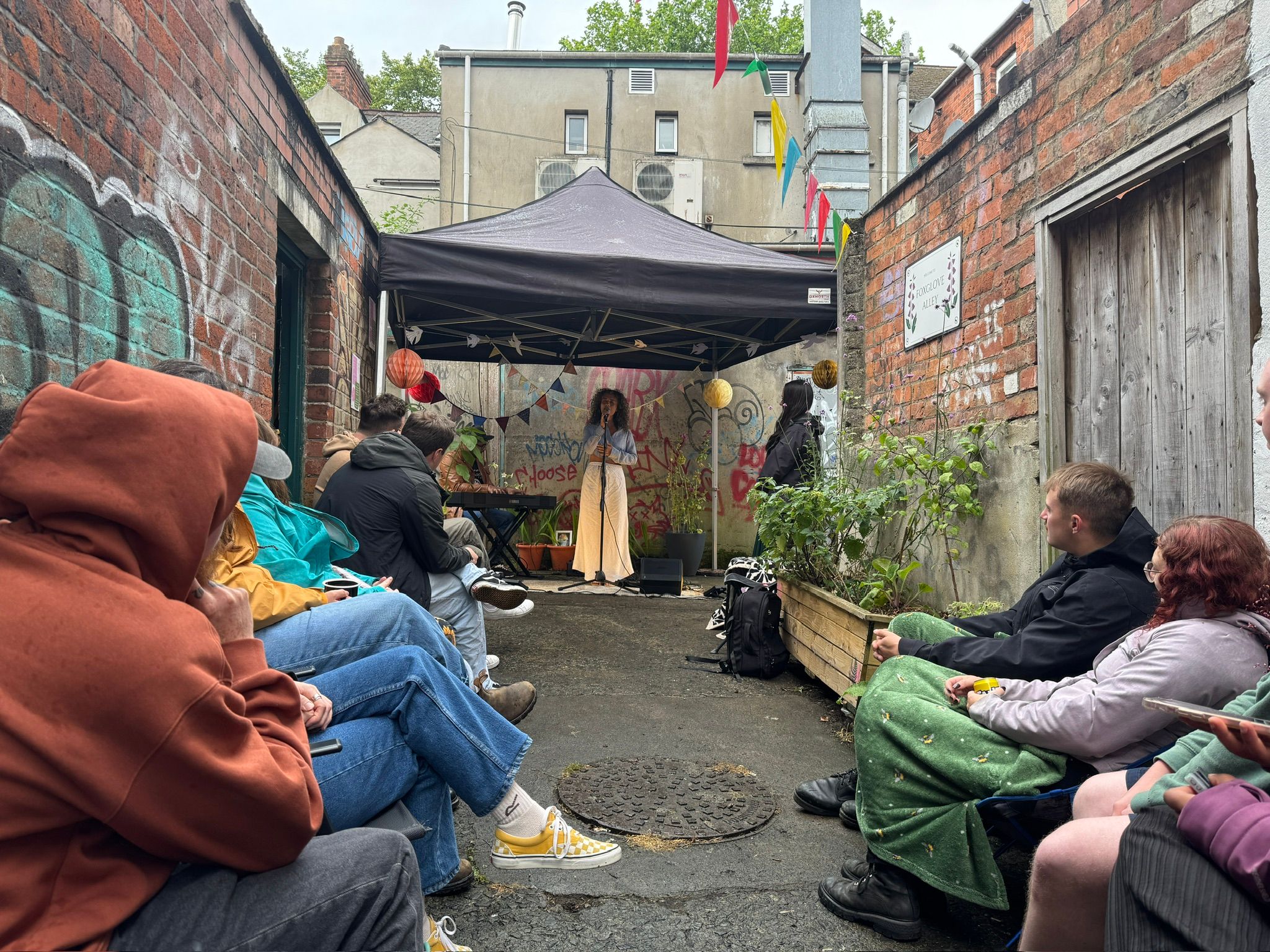 Crystal Dawn performing under a tent, while people are seated on both sides of the alleyway, looking at her