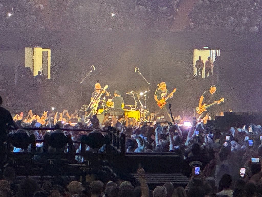 Metallica performing on a stage at the centre of the stadium. The photo is blurry because the stage is at quite a distance from where I am photographing.