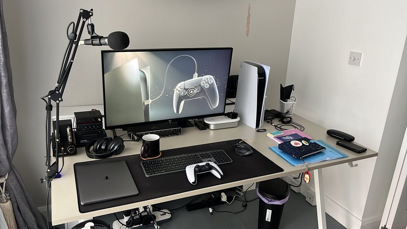 Desk setup featuring a monitor and PS5. The PS5 is turned on and the monitor displays its initialisation screen.