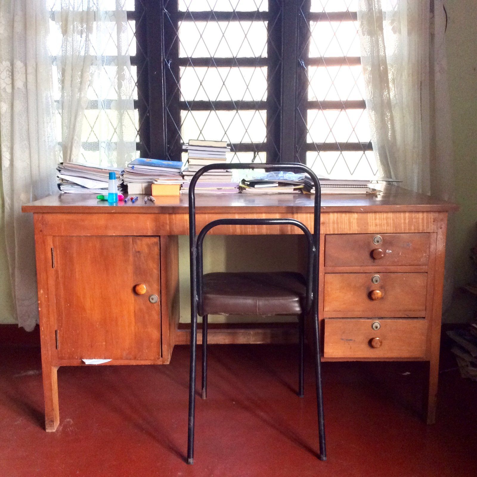 A desk, with some stacks of books on it, and a chair
