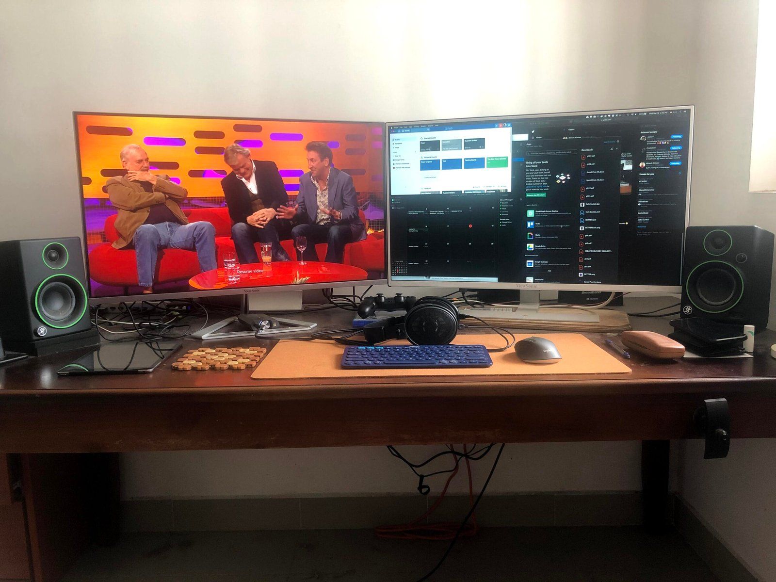 Desk setup featuring two monitors, speakers, wireless keyboard and mouse, and headphones.