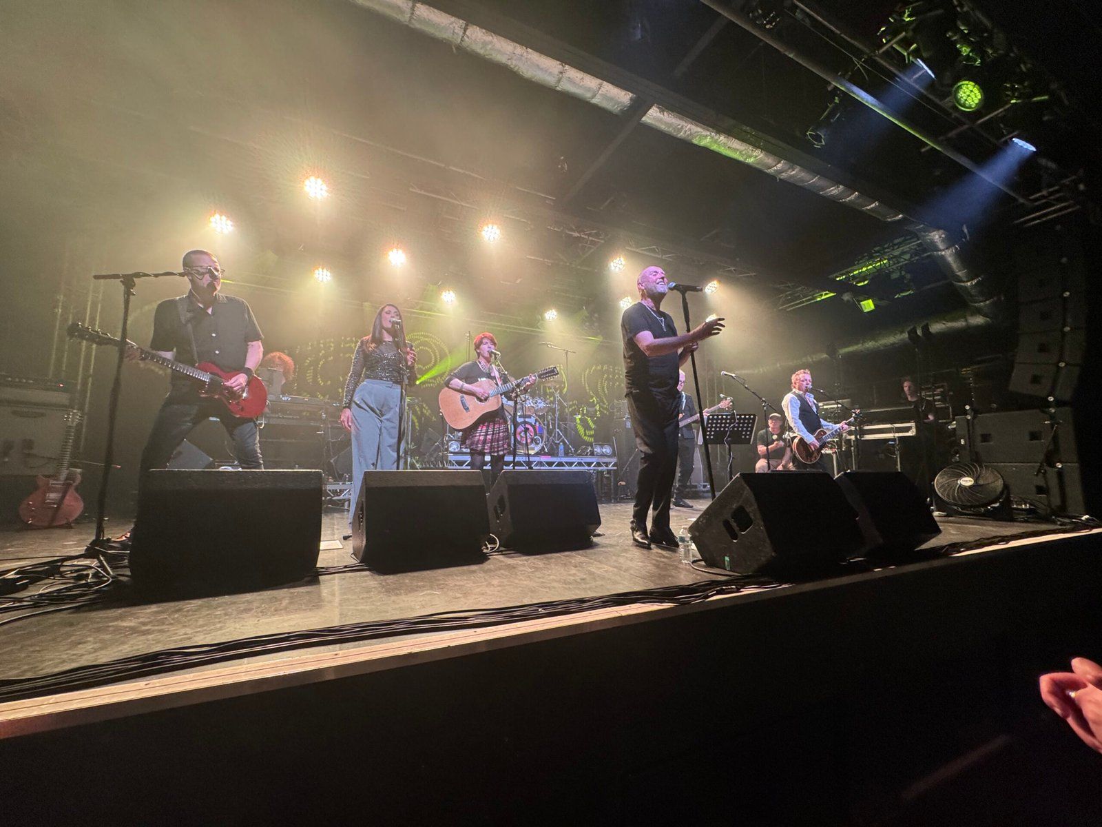 The band performing on stage while bright lights illuminates from the back