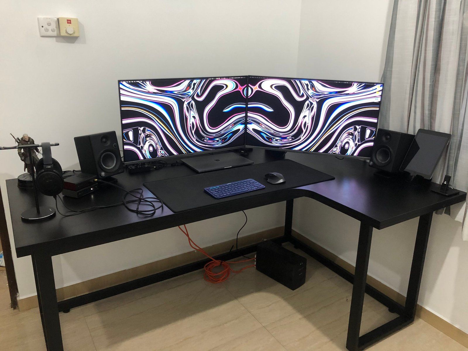 Desk setup featuring two monitors, speakers, wireless keyboard and mouse, and headphones.