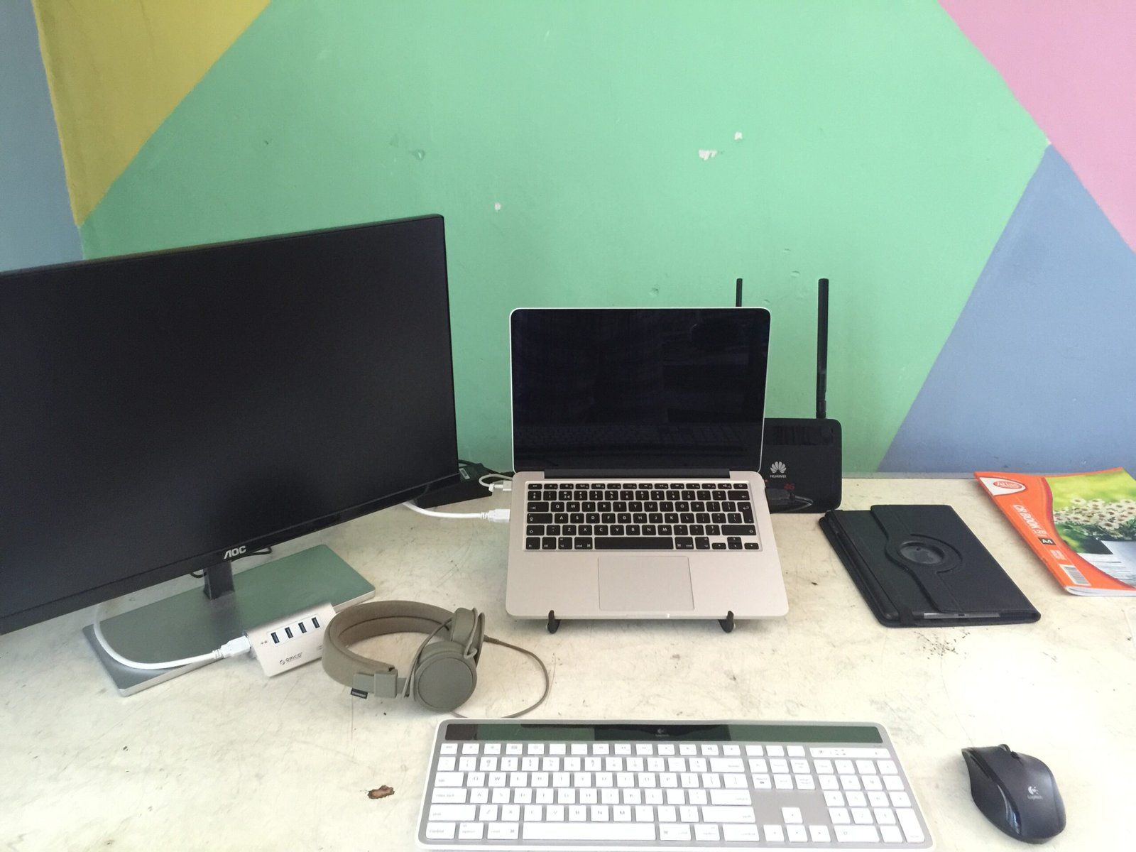 Desk setup featuring a laptop in the centre, resting on a stand, and a monitor on the left.