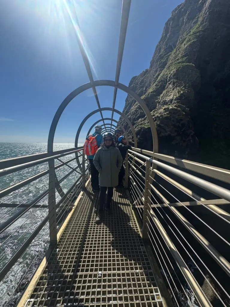 Nuwani posing for a photo in the middle of a tubular metal bridge. The rest of the group can be seen behind her.