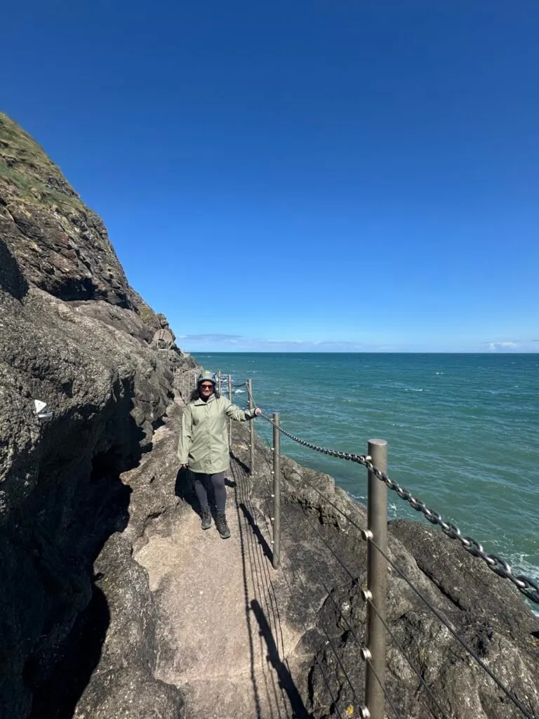 Nuwani standing on the cliff path holding the fence on her left.
