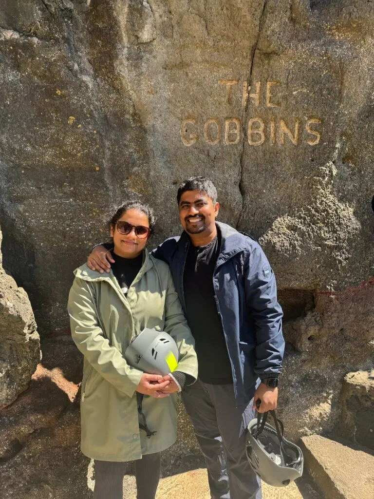 A photo of Nuwani, on the left, and I, on the right. Nuwani is wearing a light green coat and I a green one. We both have hard hats in our hands.