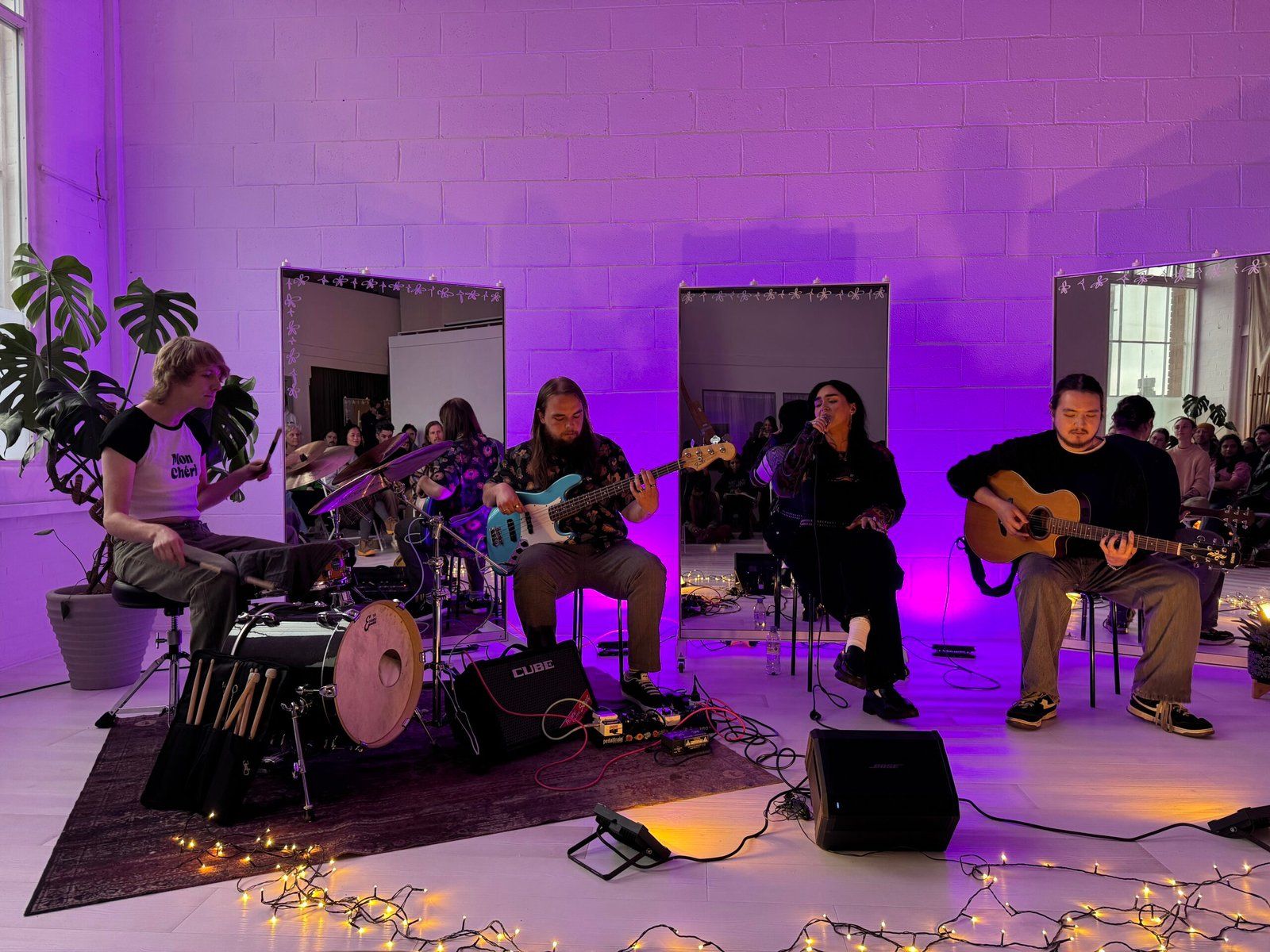 The band Vera performing. They are all seated, and purple light illuminates the space.