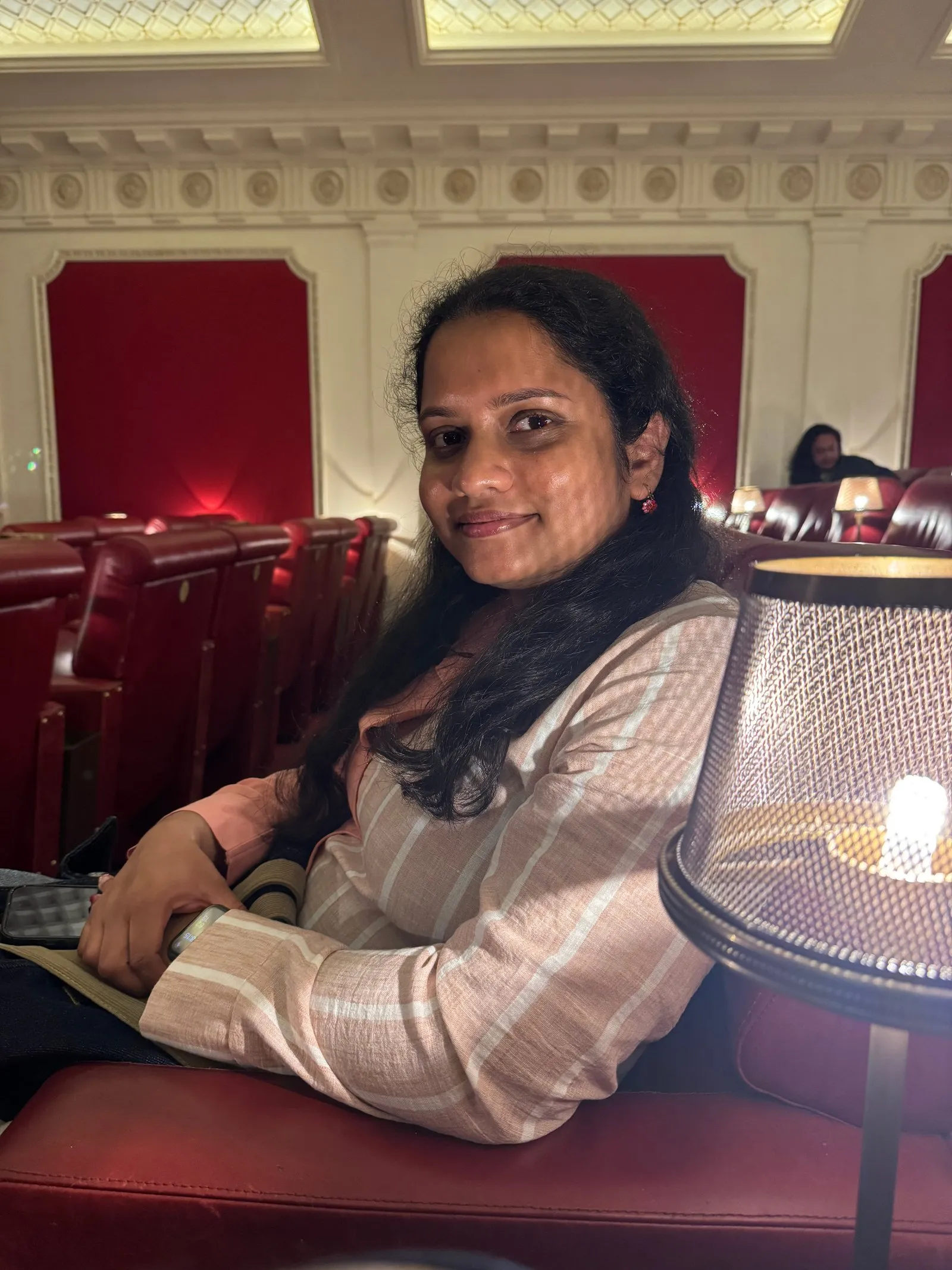 Nuwani on the seat next to me at the cinema, illuminated by one of the small lamps installed next to every seat.
