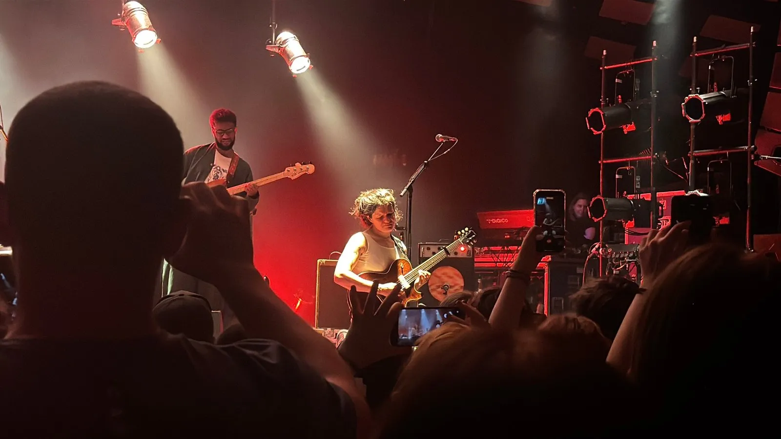 Adrianne Lenker on her knees while performing the solo of the song Not. Many audience members have their phones out, filming the moment.