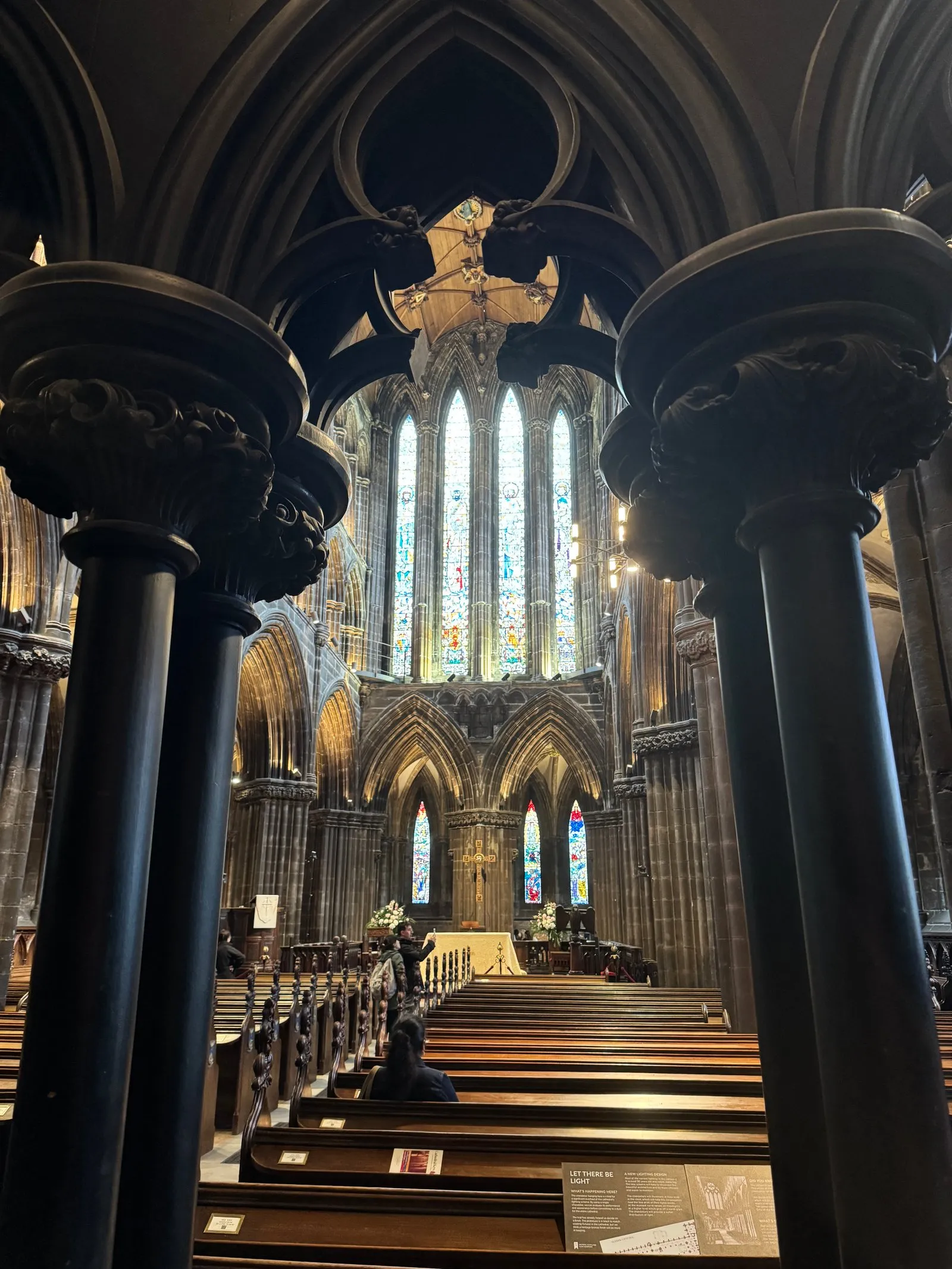The stained glass windows of the choir, as seen through some wooden columns.