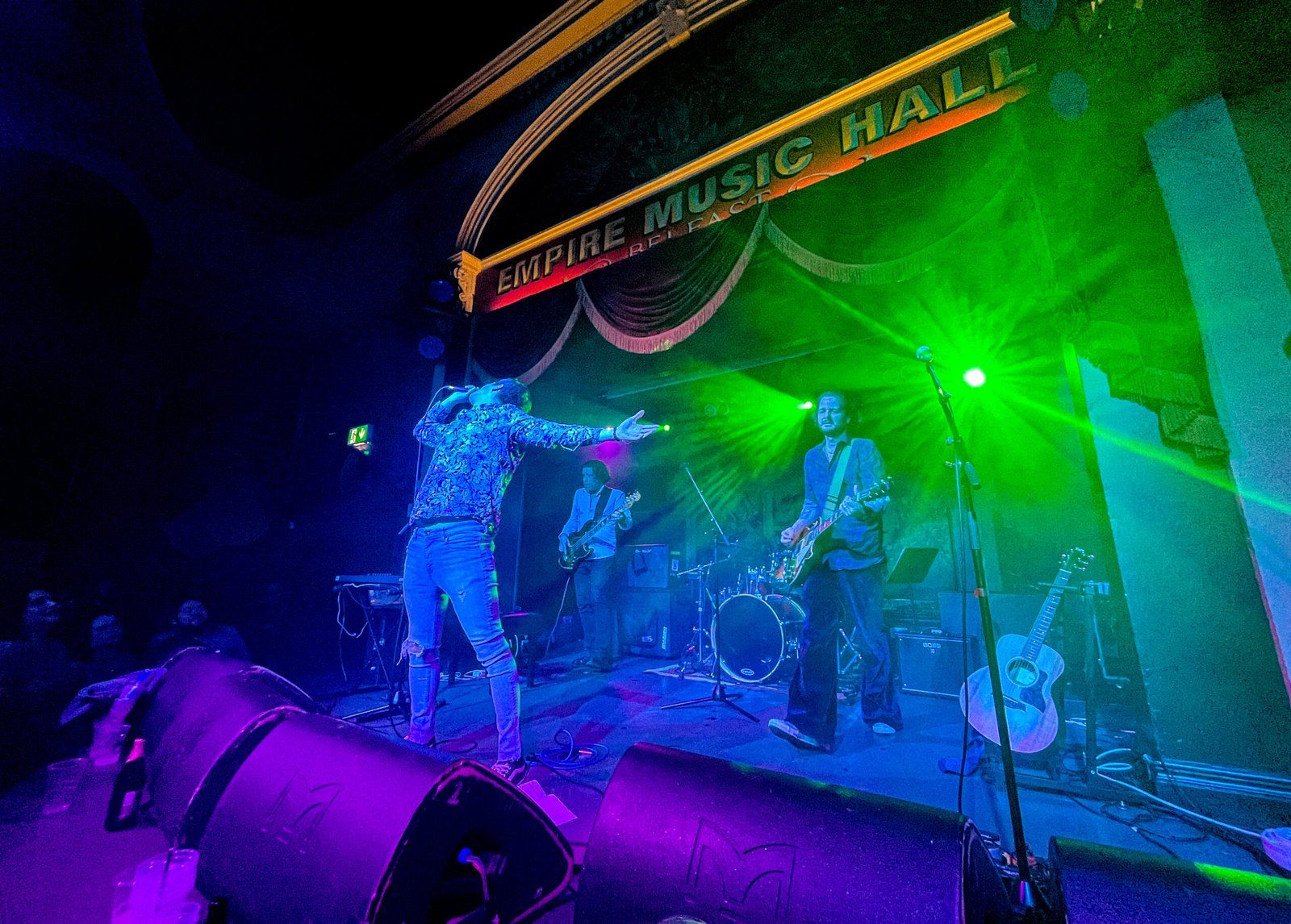 The band on stage, with bright lights illuminating it, at the Empire Music Hall.