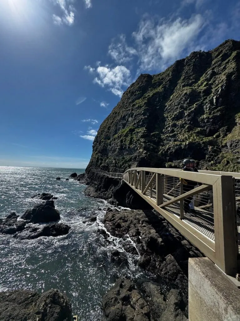 A bridge and a section of the walking path with the horizon in the background. Two people can be seen on the bridge, talking to each other.