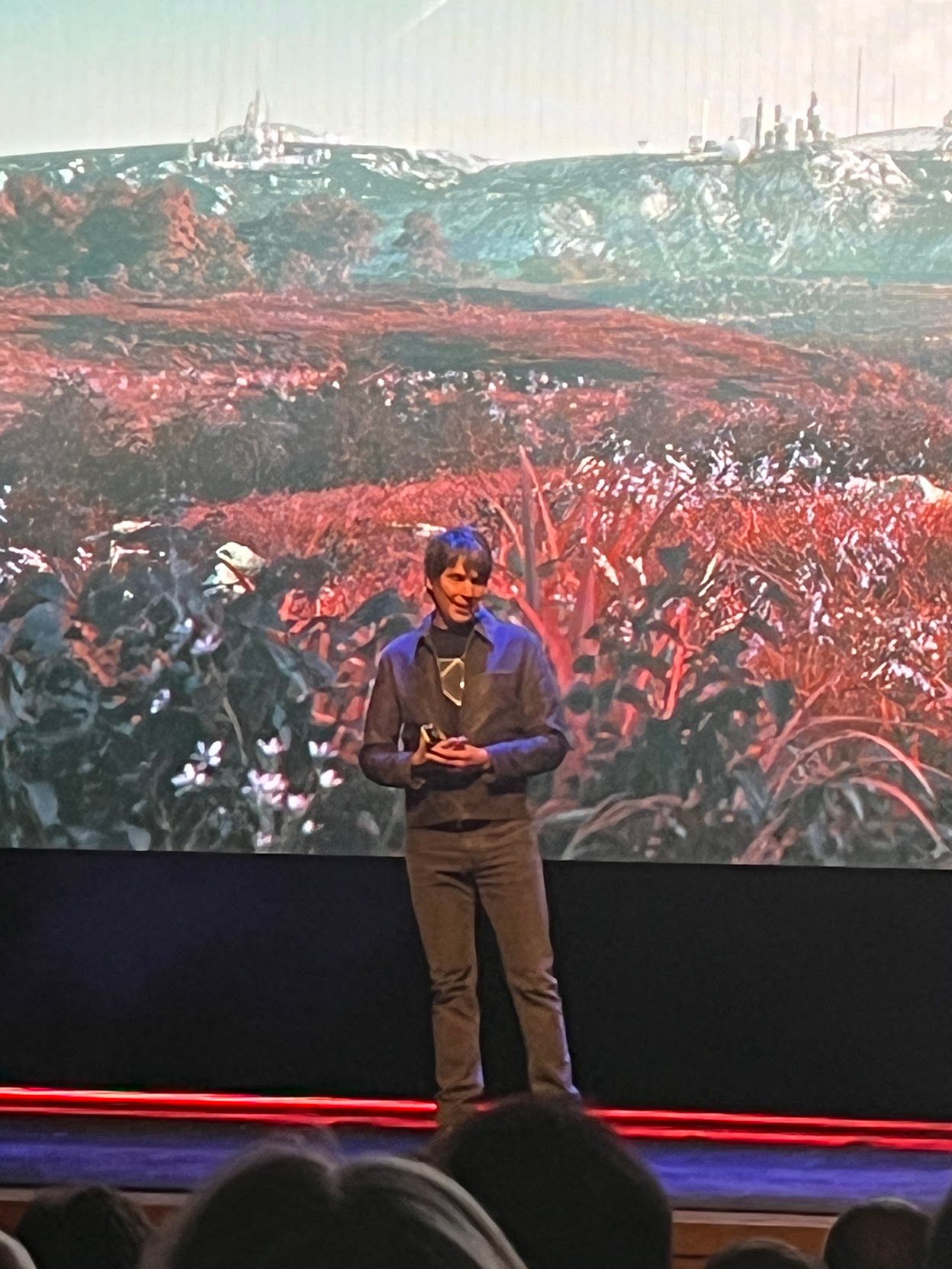 Prof Cox on stage, there is a large LED screen behind him