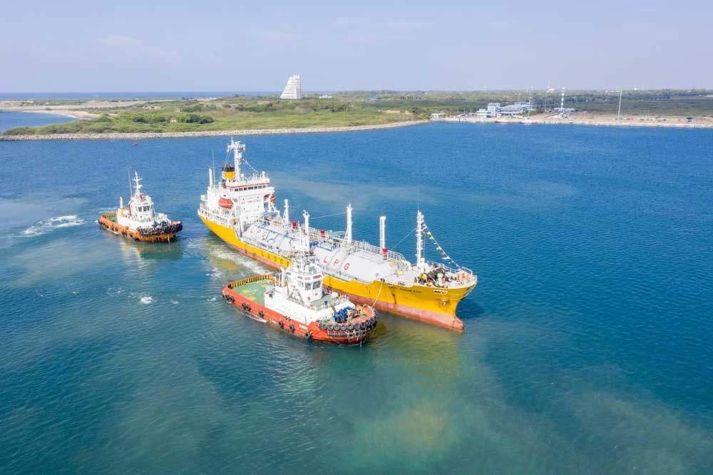 A large ship accompanied by two smaller vessels in the port of Hambantota