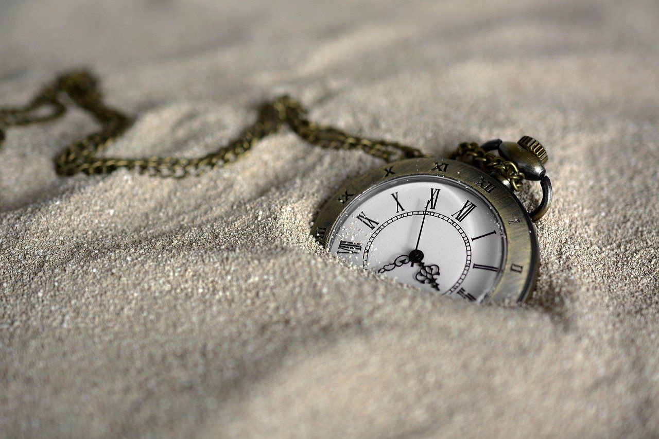 A watch half-buried in sand