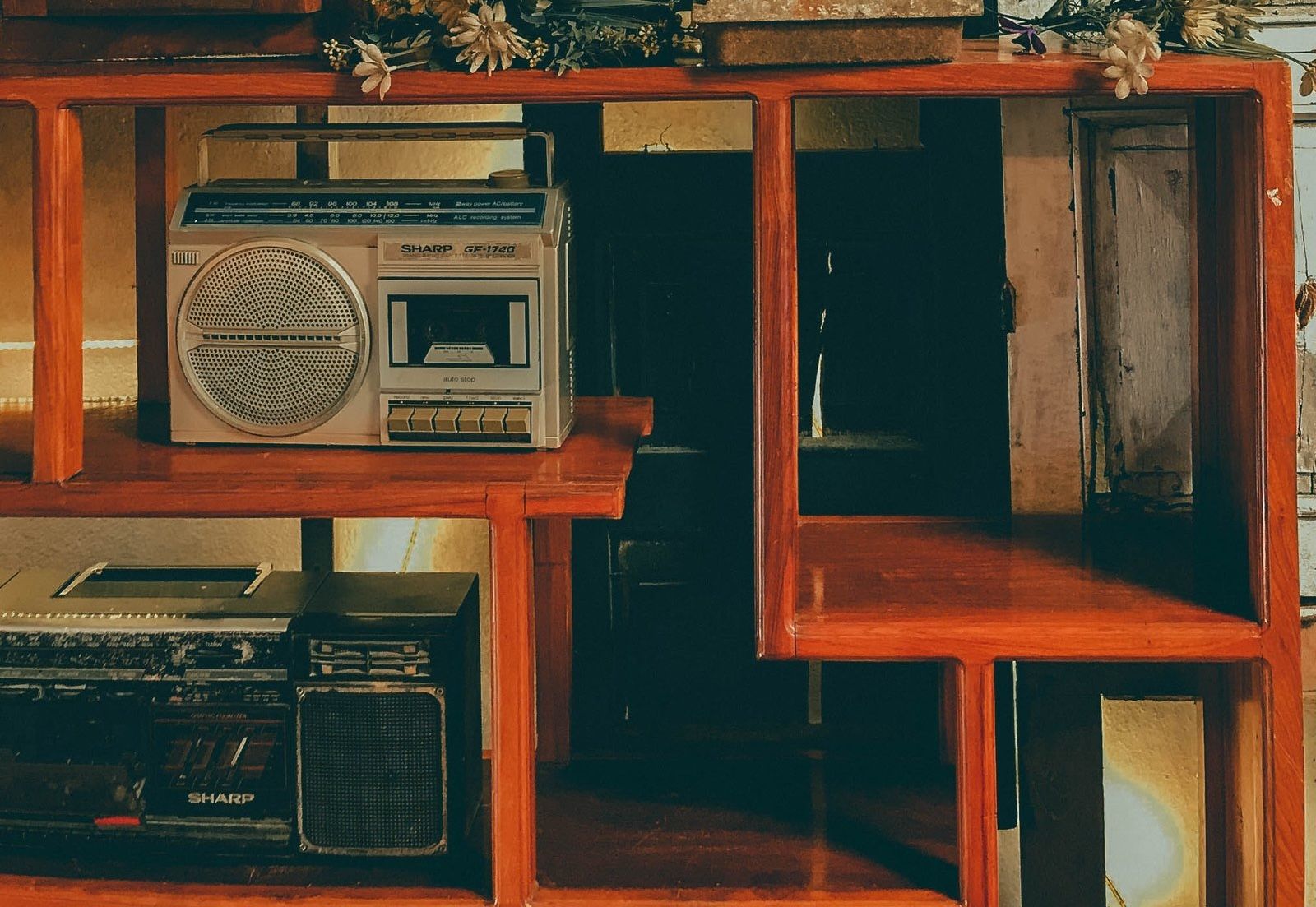 Two old "Sharp" radios sitting on a wooden shelf